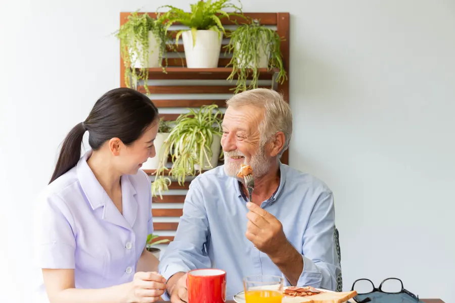 Support worker sharing a meal with an older man at home