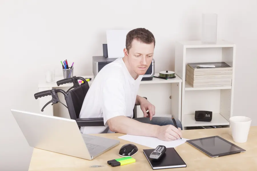 Man using a wheelchair working at a desk at home